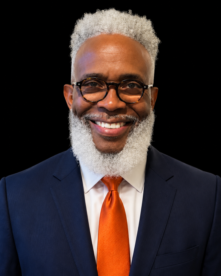 Eric Lawrence Frazier, MBA, wearing glasses, a navy suit and an orange tie